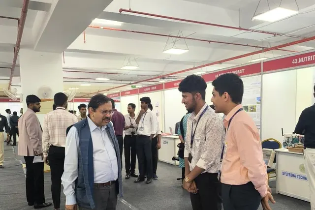 Prof. Debabrata Das in conversation with two Vyanika founders standing on the sensor mat at an exhibition hall.