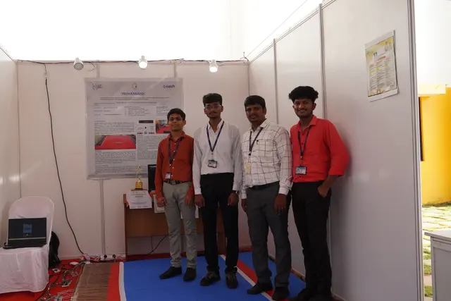 Three team members standing at their exhibition stand beside the sensor mat and a display screen.